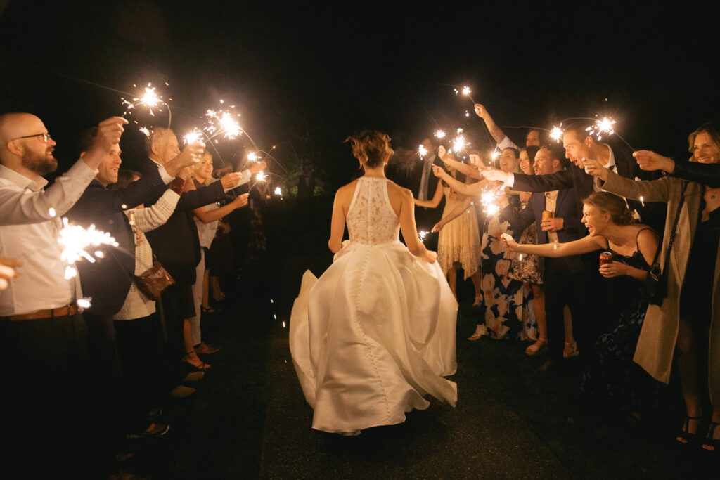 Newly married bride runs down the middle of the sparkler exit with her friends and family cheering