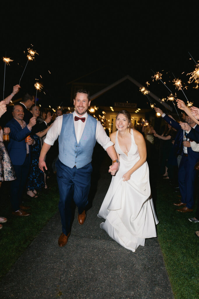 Newly married bride and groom holding hands as they run down the middle of the sparkler exit after their wedding in Seattle